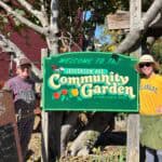 Volunteers stand on either side of the Jefferson Avenue Community Garden sign
