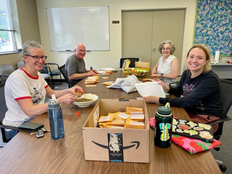 Volunteers sit around a table and smile for the camera