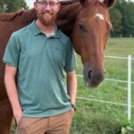 Connor Almond stands by his horse on his farm in Amelia County